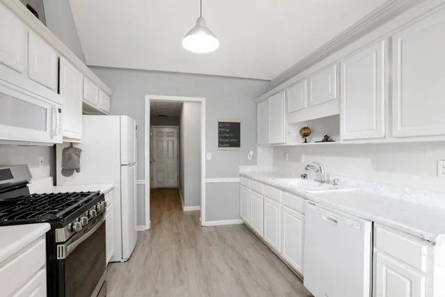 a kitchen with white cabinets and appliances