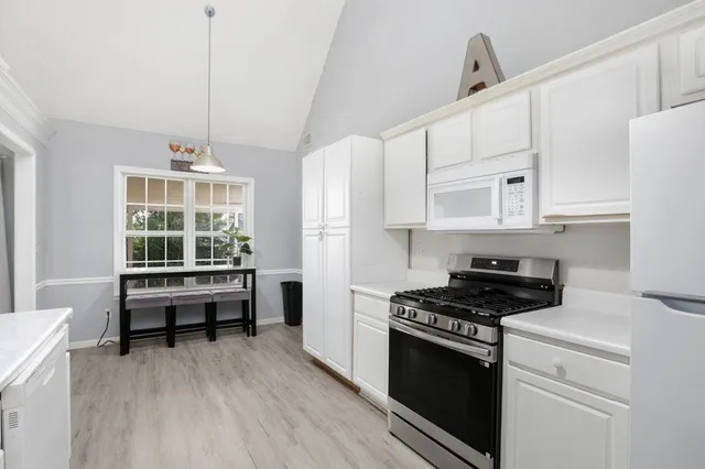 a kitchen with stainless steel appliances a stove a sink and white cabinets