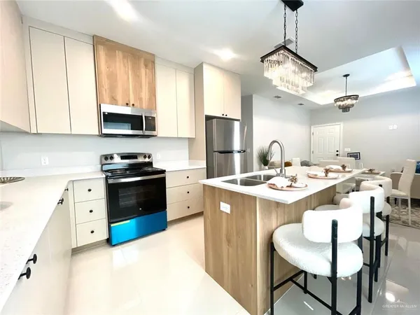 a kitchen with stainless steel appliances kitchen island a table chairs and a refrigerator