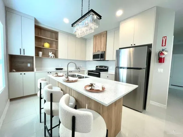 a kitchen with stainless steel appliances a refrigerator a sink a stove a dining table and chairs