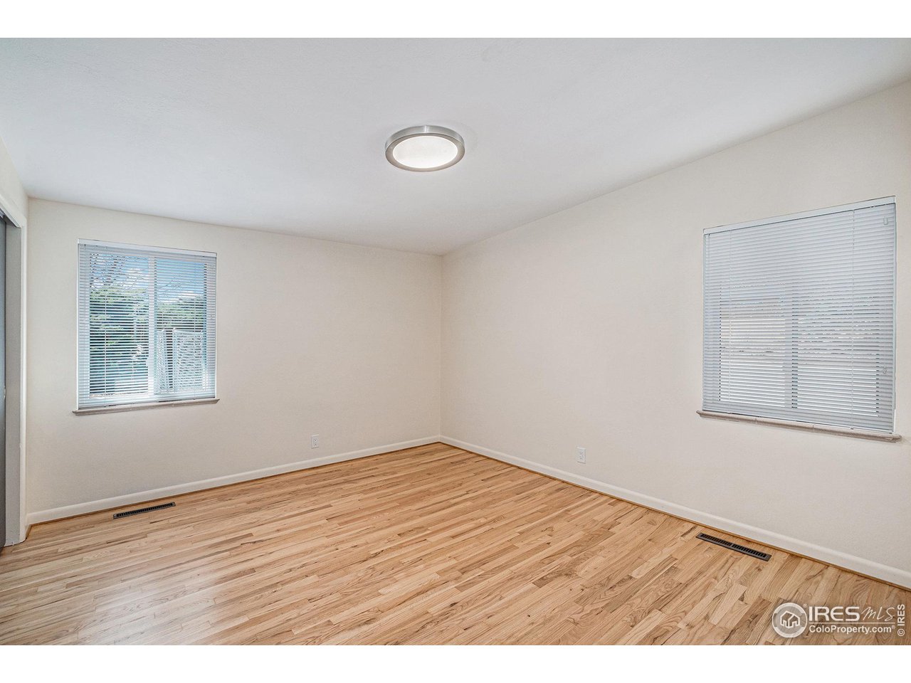 613 Skyline Drive Fort Collins, CO 80521 - Photo 12 of 19 an empty room with wooden floor and windows
