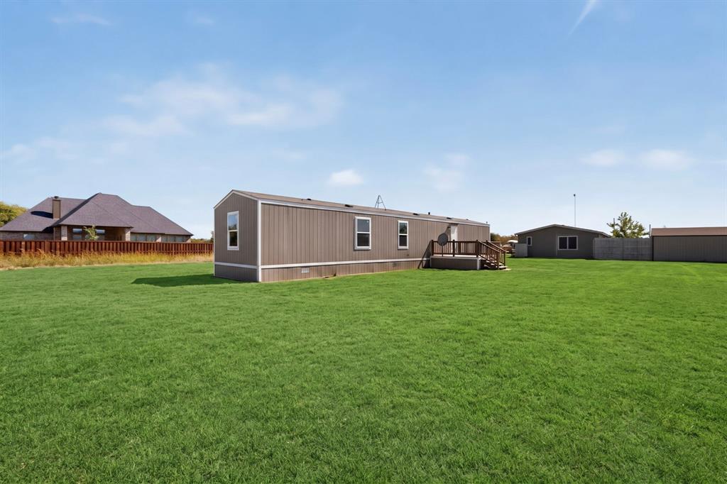 15281 Stice Road Krum, TX 76249 - Photo 21 of 22 Expansive green lawn, brown siding, multiple windows, wooden deck, wooden steps