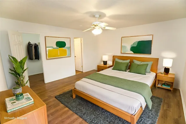 a bedroom with a bed lamps and wooden floor