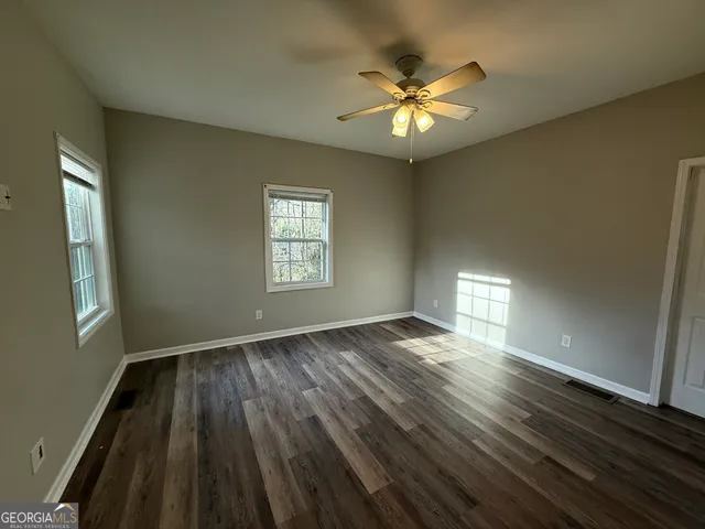 a view of an empty room with a window and wooden floor