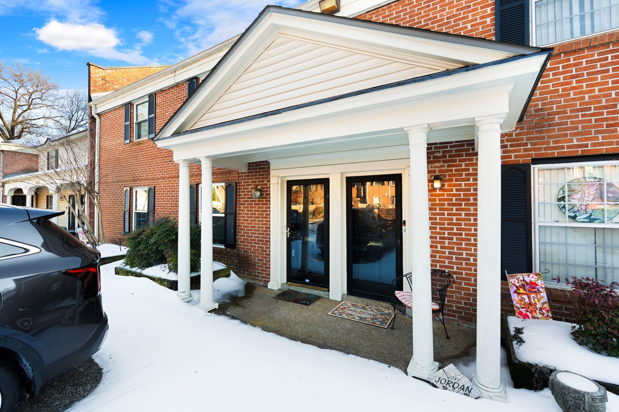 Doorway to property with brick siding and covered porch