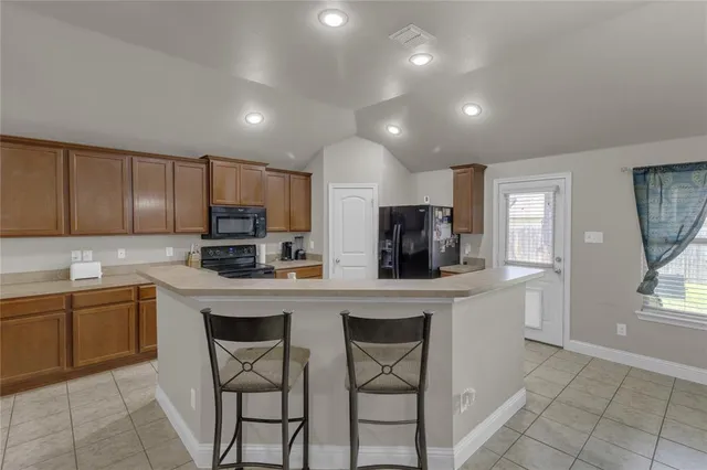 a kitchen with stainless steel appliances a sink a stove a refrigerator cabinets and a window