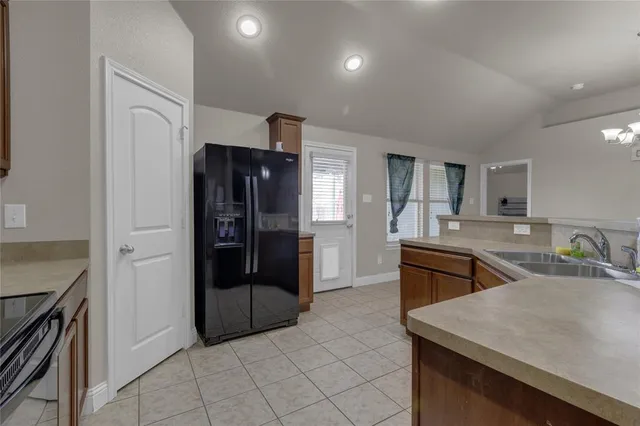 a room with stainless steel appliances kitchen island granite countertop a refrigerator and a sink