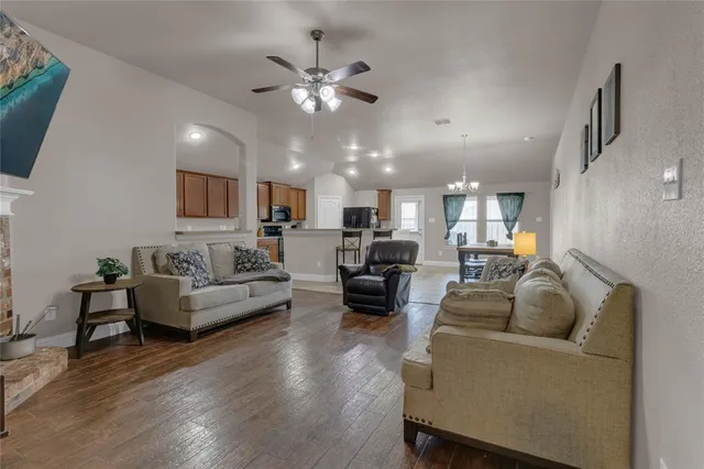 a living room with furniture kitchen view and a wooden floor