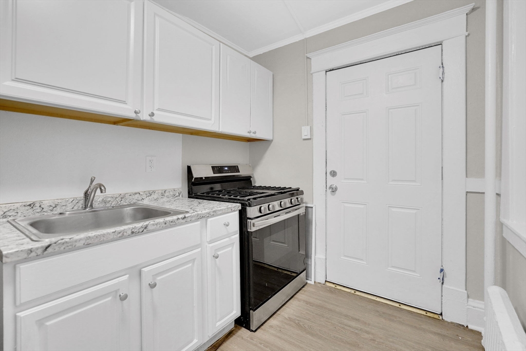 120-122 Central Street Springfield, MA 01103 - Photo 15 of 30 a kitchen with white cabinets sink and stove