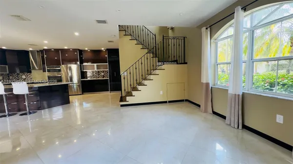 a view of kitchen with stainless steel appliances wooden floor and window
