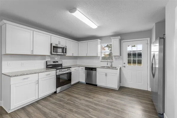 a kitchen with granite countertop white cabinets and white appliances