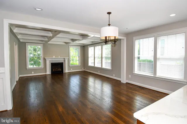 a view of a livingroom with wooden floor a ceiling fan and windows