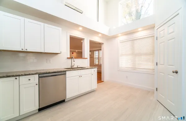 a kitchen with granite countertop white cabinets and white appliances