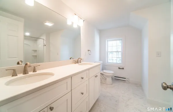 a bathroom with a double vanity sink toilet and a mirror
