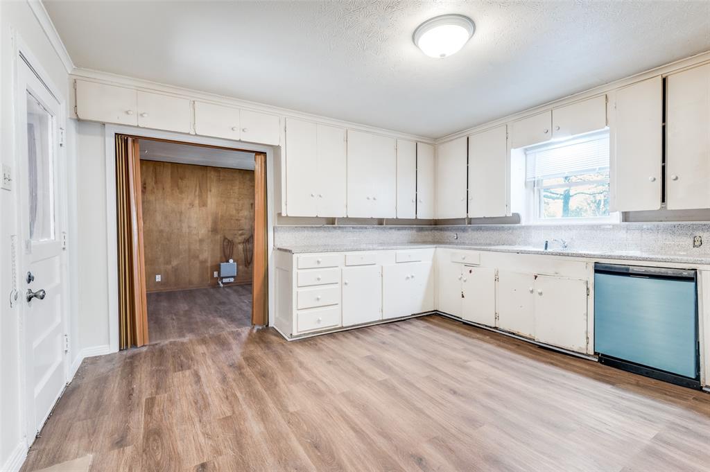 402 West Grauwyler Road Irving, TX 75061 - Photo 7 of 22 a view of a kitchen with a sink and dishwasher with white cabinets