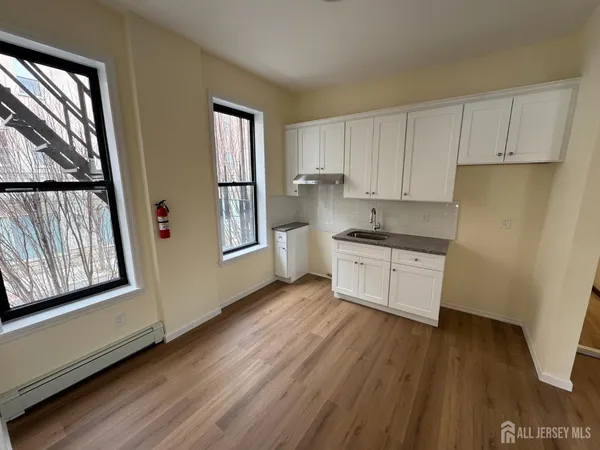 a kitchen with stainless steel appliances granite countertop a refrigerator a sink dishwasher a stove and white countertops with wooden floor