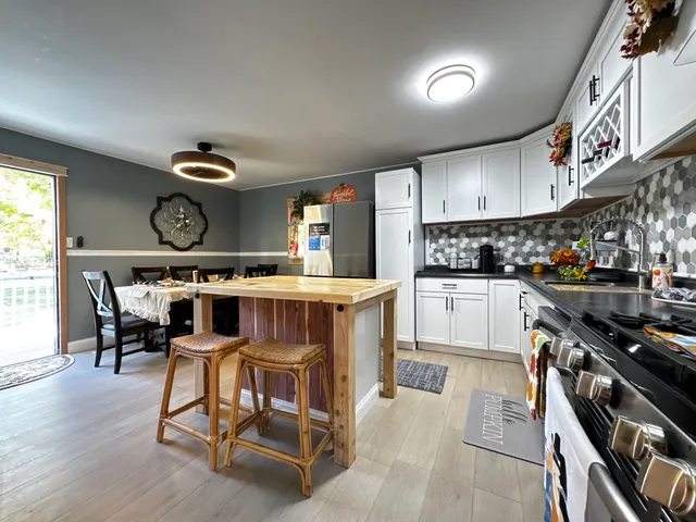 a kitchen with granite countertop a stove a sink a dining table and chairs