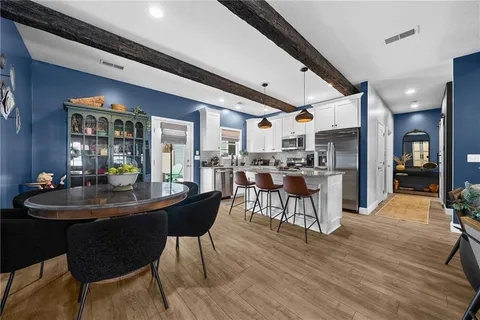 a dining room with stainless steel appliances kitchen island granite countertop a table chairs and a oven