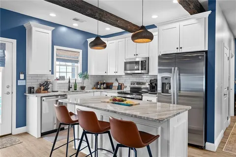 a kitchen with stainless steel appliances granite countertop a sink a stove a refrigerator cabinets and chairs