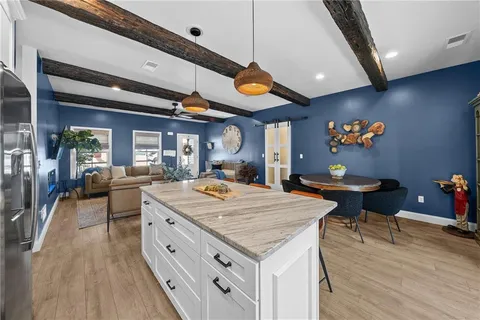 a living room with stainless steel appliances kitchen island granite countertop a table chairs and a refrigerator