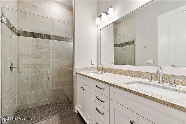 a bathroom with a granite countertop sink a mirror and shower