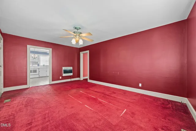 a view of an empty room with a window and a kitchen