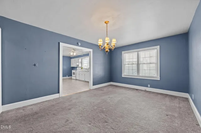 a view of an empty room with chandelier fan and windows