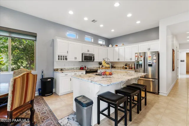 a kitchen with stainless steel appliances kitchen island granite countertop a table chairs sink and microwave
