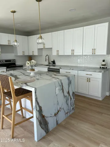 a kitchen with stainless steel appliances granite countertop a sink a stove a dining table and chairs