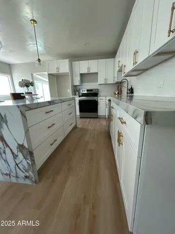 a kitchen with granite countertop white cabinets and stainless steel appliances