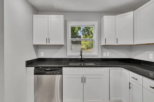 a kitchen with granite countertop white cabinets and a black appliances