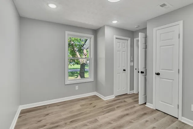 a view of an empty room with wooden floor and a window