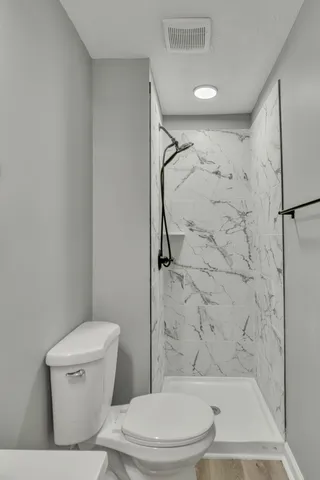 a white toilet sitting next to a bath tub and a shower