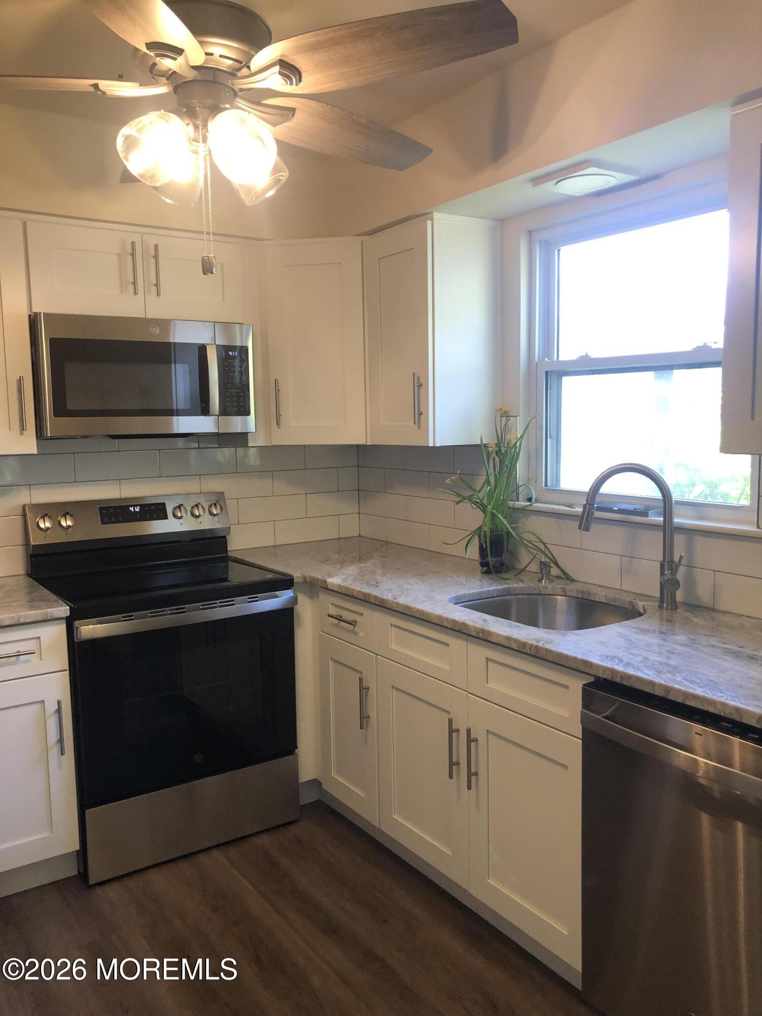 6 Dickinson Road Brick, NJ 08724 - Photo 3 of 17 a kitchen with stainless steel appliances granite countertop a sink a microwave a stove and white cabinets