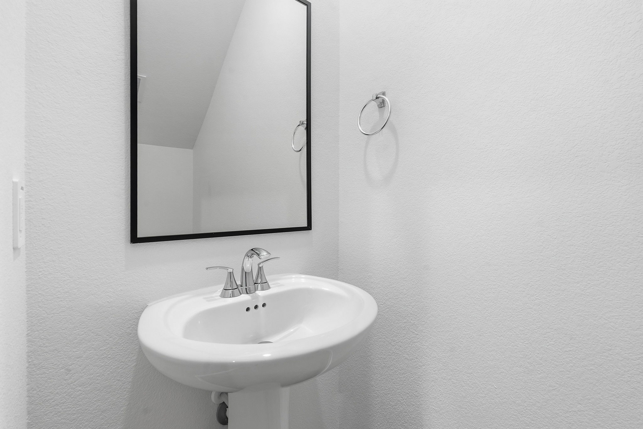 164 Cinnabar Lane, Unit 4 Kyle, TX 78640 - Photo 20 of 23 Pedestal sink with chrome faucet, complemented by a rectangular mirror with a black frame and a chrome towel ring