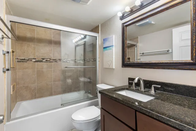 a bathroom with a granite countertop sink a toilet and shower