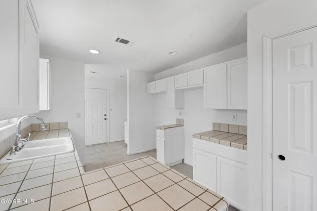 a kitchen with white cabinets a sink stove and refrigerator
