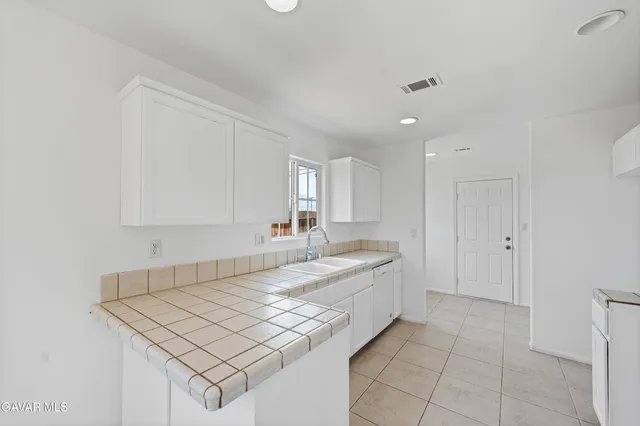 a large white kitchen with a sink and cabinets