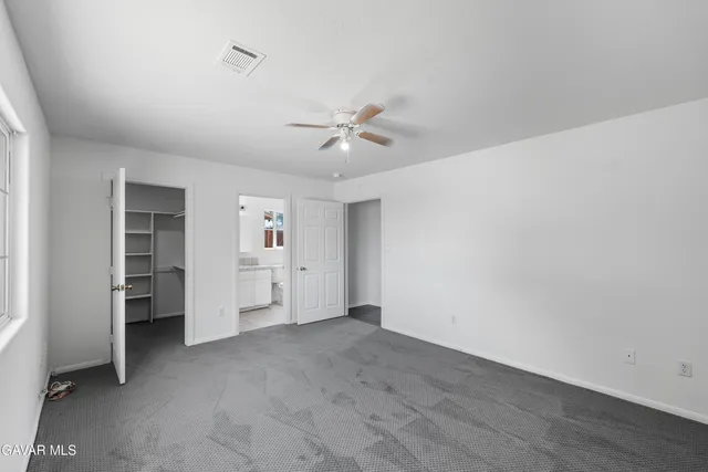 an empty room with closet and a ceiling fan