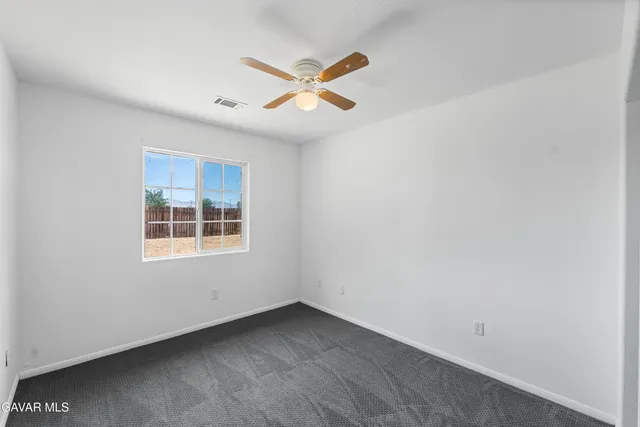 an empty room with window and ceiling fan