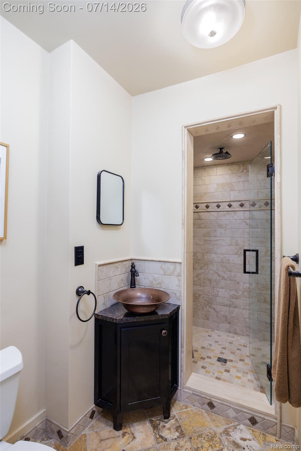 189 Cloverly Road Grosse Pointe, MI 48236 - Photo 27 of 96 Bathroom featuring a copper vessel sink, dark wood vanity with a stone countertop, a glass-enclosed shower with tile surround, and irregular stone flooring