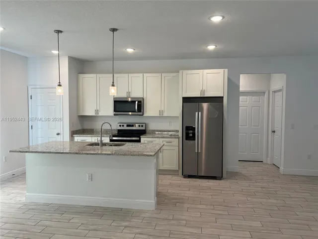 a kitchen with stainless steel appliances granite countertop a refrigerator a stove a sink and a microwave