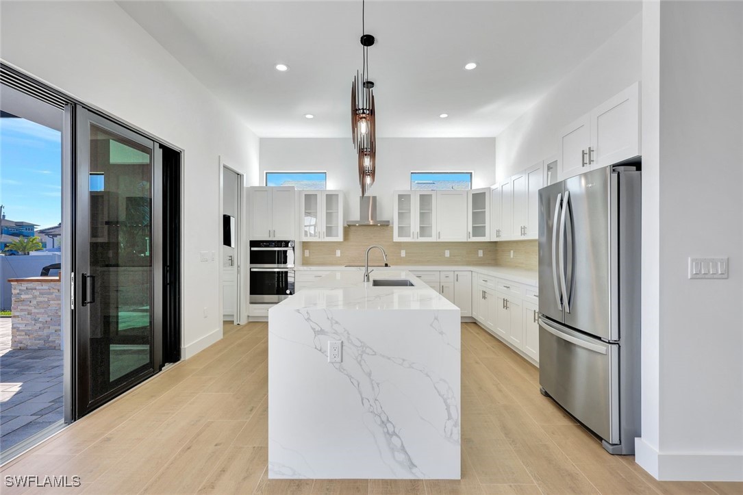 1 Southwest 33rd Place Cape Coral, FL 33991 - Photo 10 of 38 a large kitchen with stainless steel appliances kitchen island granite countertop a refrigerator and a sink