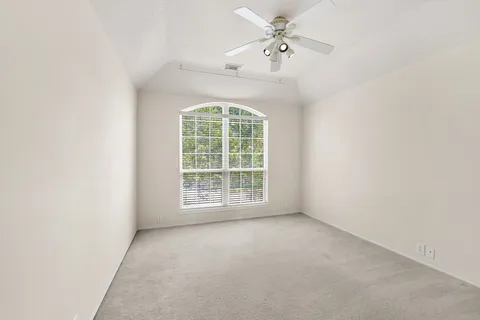 an empty room with windows and fan