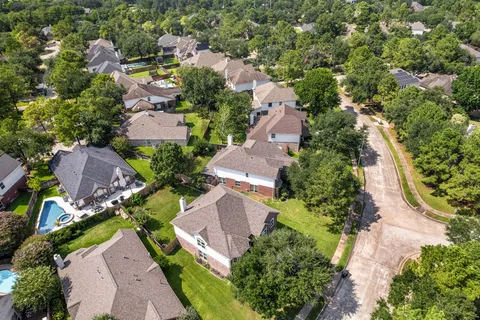 a view of a white house with a large windows and a yard with plants and large trees
