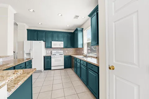 a kitchen with kitchen island granite countertop a sink stove and cabinets
