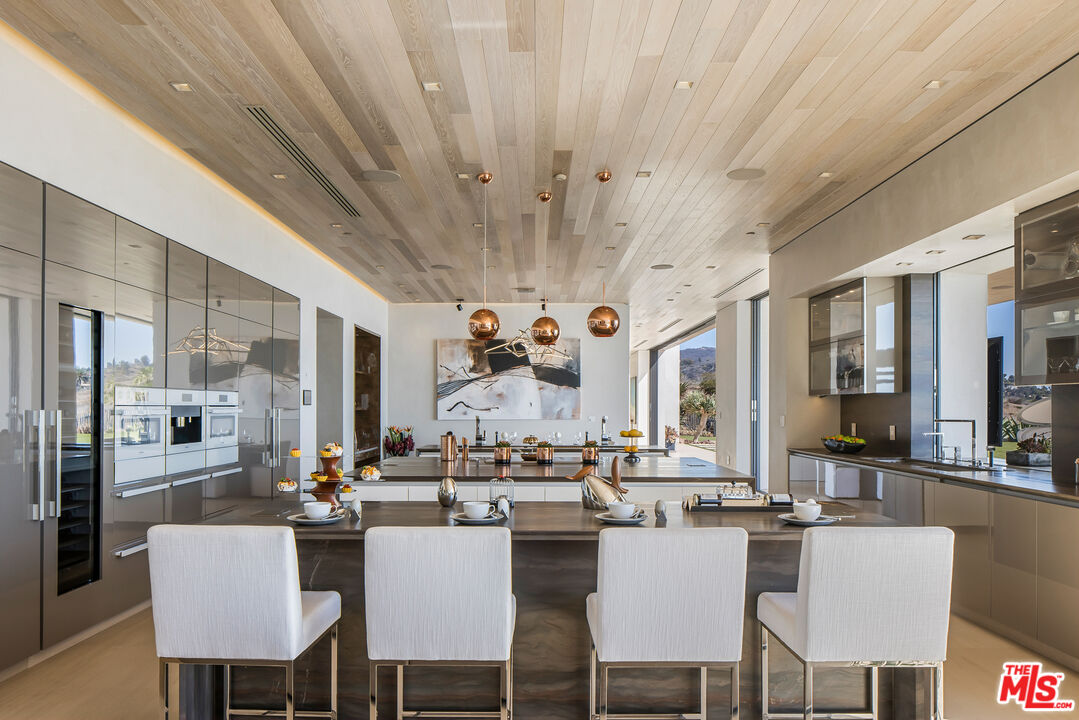 5046 Carbon Beach Terrace Malibu, CA 90265 - Photo 22 of 75 a dining room with stainless steel appliances a table chairs and a chandelier
