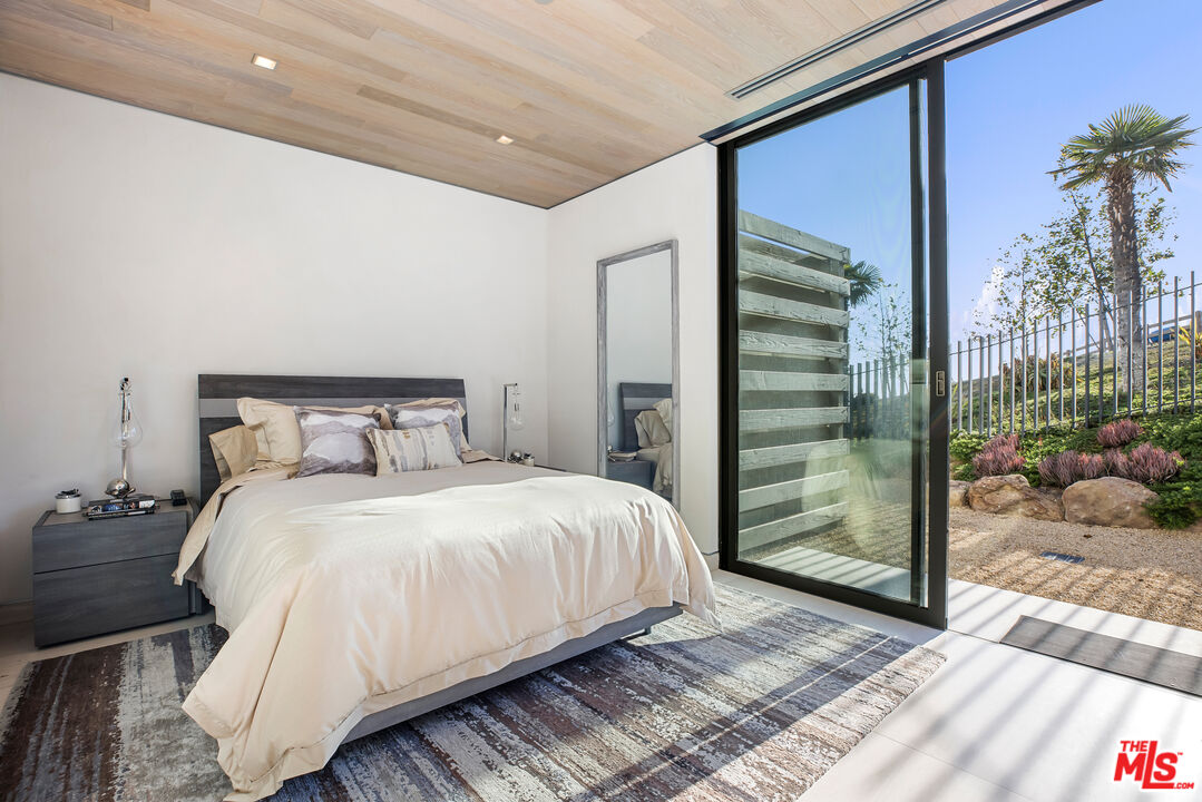 5046 Carbon Beach Terrace Malibu, CA 90265 - Photo 50 of 75 a bedroom with a large bed and a chandelier