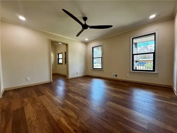 a view of empty room with wooden floor and fan