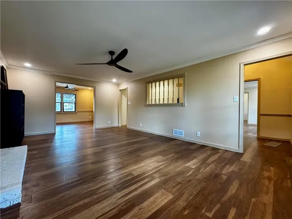 a view of an empty room with window and wooden floor